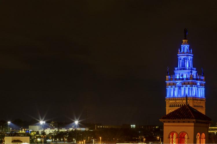 Blue and gold lights illuminate Plaza building and Durwood Stadium.