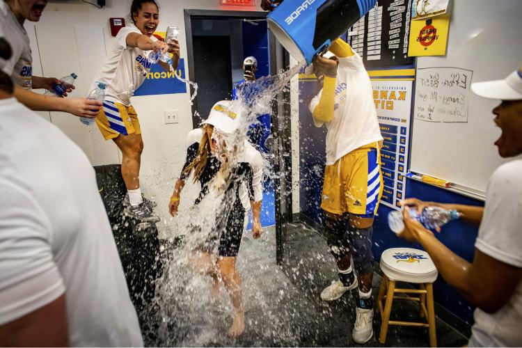 Locker room celebration of water being poured over Women's Basketball Coach Jacie Hoyt