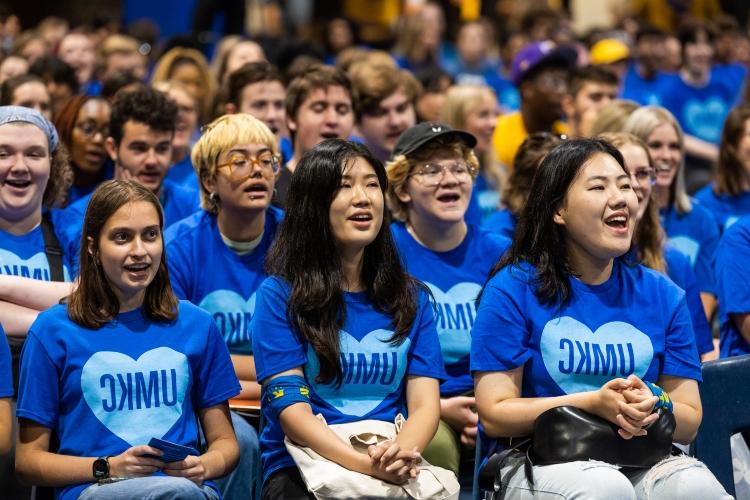 students sit in rows singing the alma mater at Convocation