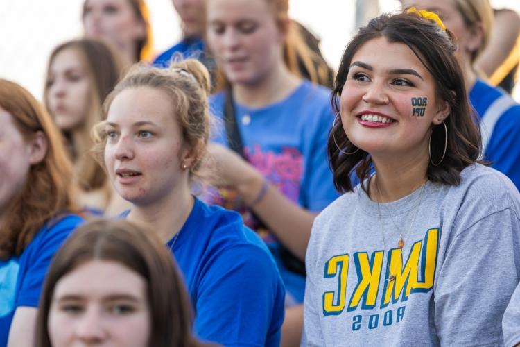 A student watches the soccer match smiling with a roo sticker on her cheek