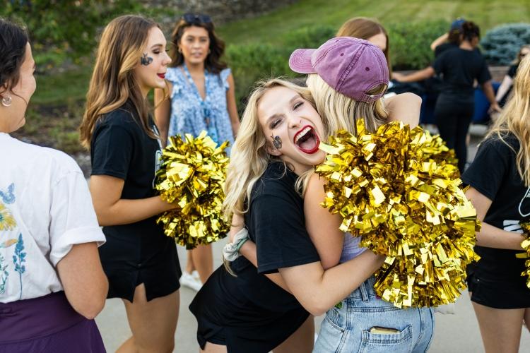 a dance team member embraces a friend at Durwood Stadium