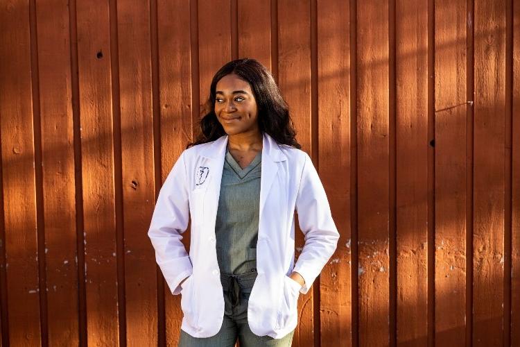 Dubemi Okocha, a student in the accelerated B.A./M.D. program, posing in a white coat