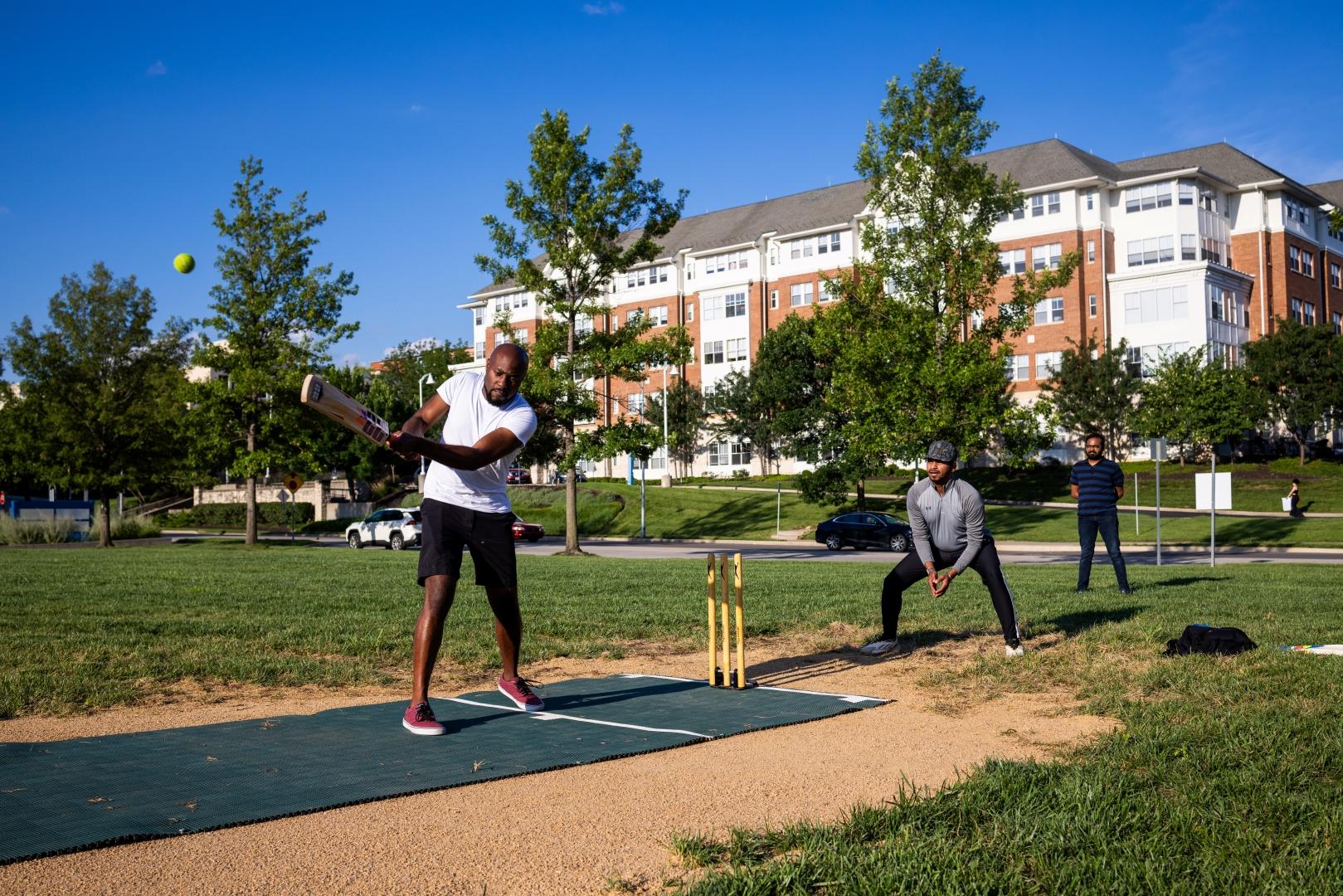 Picture of three students playing cricket