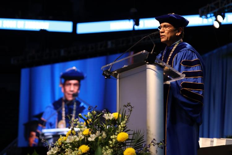 Chancellor Mauli Agrawal stands at a podium in regalia 