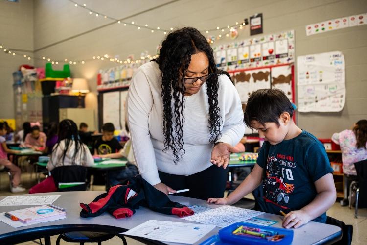 Kayla helps a young student with homework inside Trailwoods Elementary